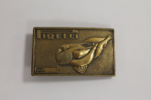 After Salvador Dali - A Pirelli brass belt buckle, 4.5 cm x 7.5 cm. CONDITION REPORT: Good