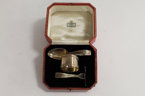 A silver spoon and pusher, together with matching napkin ring, retailed and cased by Harrods, London