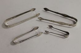 Two pairs of Georgian silver sugar tongs, together with two pairs of smaller silver sugar nips. (