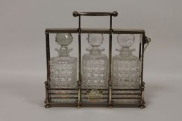 An Edwardian silver-plated three bottle Tantalus and key, width 32 cm. Excellent condition, with
