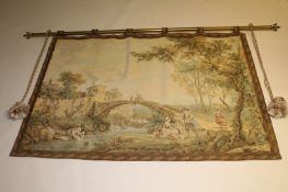 A tapestry wall hanging on brass rail depicting a bridge over a rocky stream, 200 cm x 146 cm.