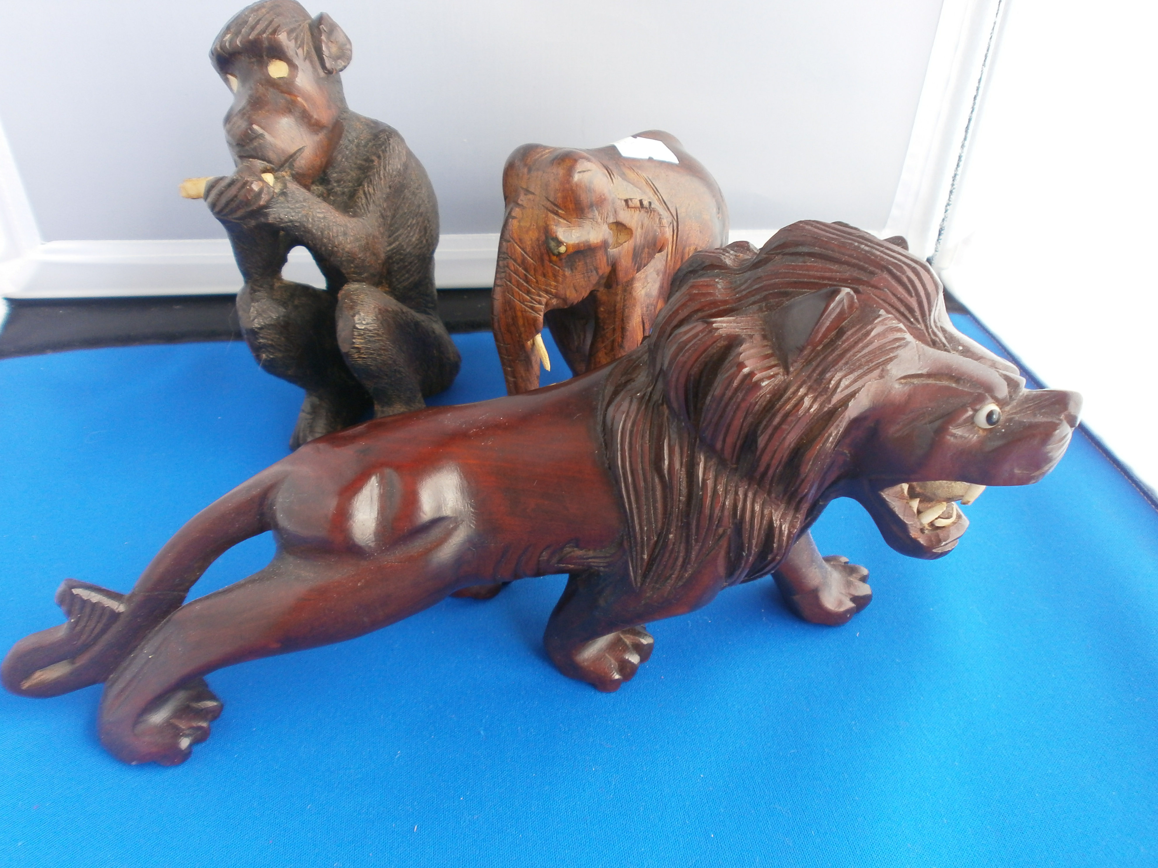 Three carved wooden animals, lion, elephant and monkey