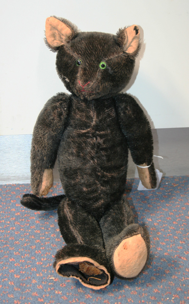 A mid-20th Century black mohair teddy bear with black and green eyes, stitched snout and jointed