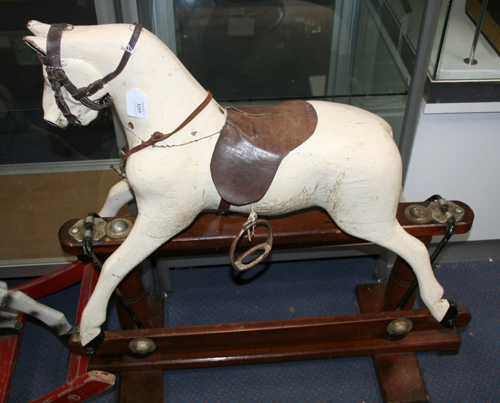 An early 20th Century painted wooden rocking horse with black and white eyes and later harness and