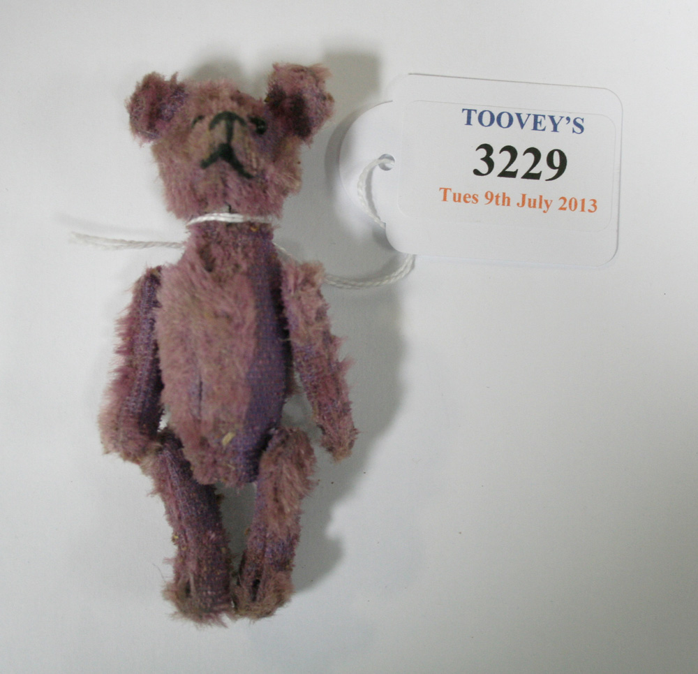 A Schuco compact purple teddy bear, the removable head with black eyes and stitched nose, the hinged