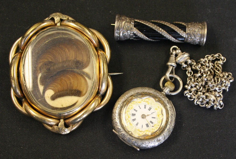 A Victorian gilt metal shaped oval brooch glazed with a feathered hair locket compartment within