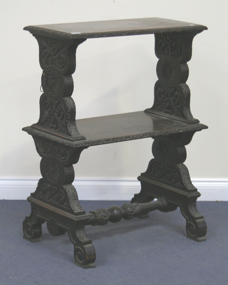 A Victorian oak two tier stand, carved with leaves and flowers, on scrollwork supports, united by