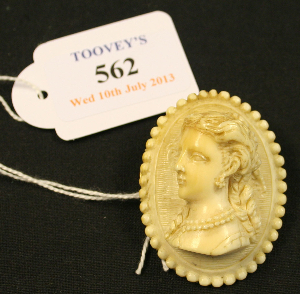 A carved ivory oval cameo brooch designed as the portrait of a lady within a beaded surround.