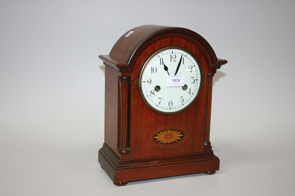 An early 20th Century mahogany mantel clock with eight day movement striking on a gong, the enamel