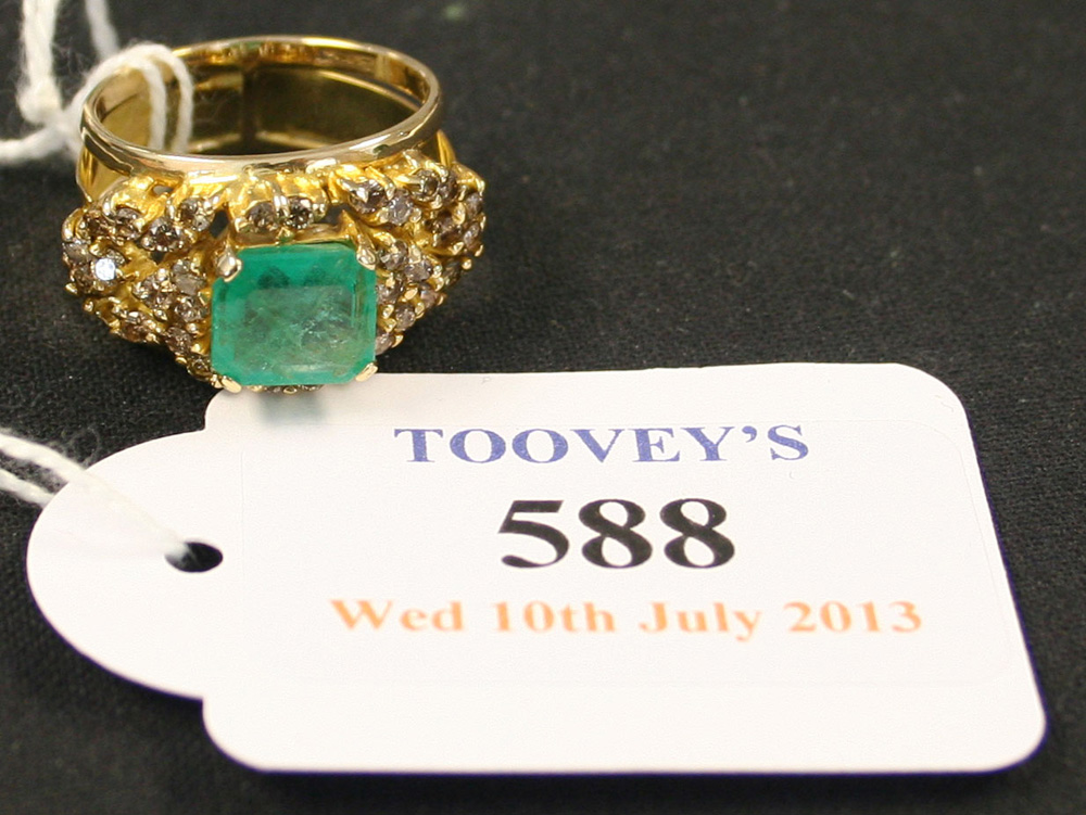 A gold, emerald and diamond ring, claw set with the rectangular step cut emerald at the centre,