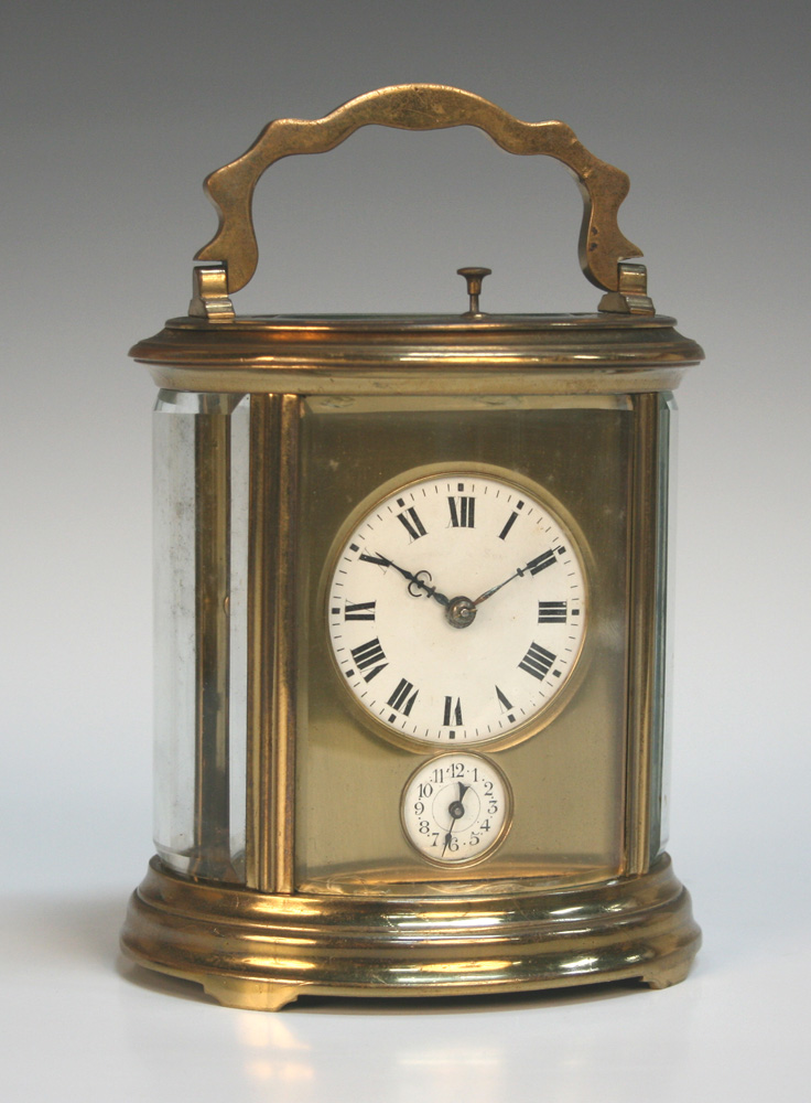 A late 19th Century French brass oval cased carriage alarm clock with eight day movement repeating