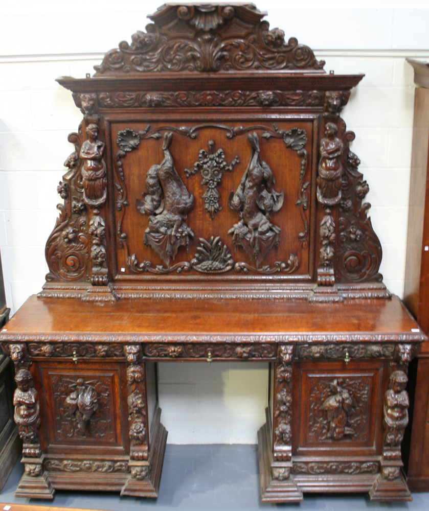 A large late 19th Century oak sideboard, profusely carved with foliate scrolls, masks and flowers,