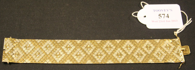 An 18ct two colour gold bracelet in a wide honeycomb link design, with stylized floral motifs and
