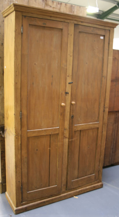 An early 20th Century stripped pine hall cupboard, the moulded pediment above a pair of fielded