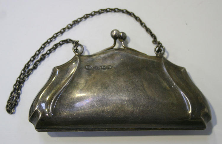 A George V silver purse with a leather lined interior, on a snap clasp fitted with a carrying chain,