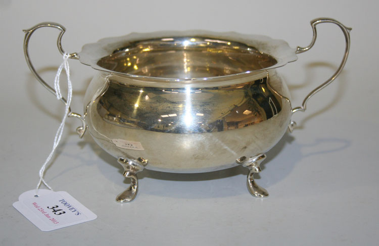 A George V silver circular two handled bowl with petal rim, raised on scroll feet, Birmingham 1920