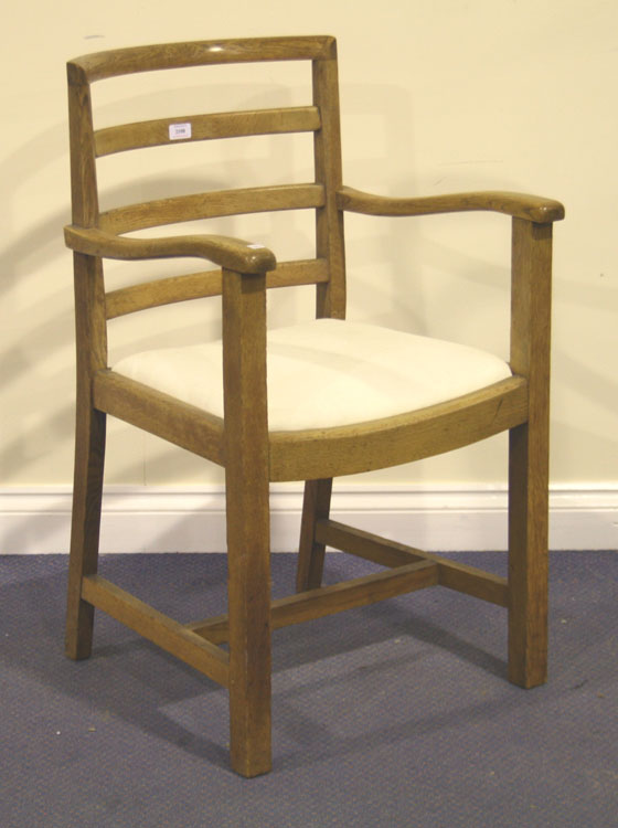 An early 20th Century oak ladder back elbow chair by Heal`s, the drop-in seat above block legs.