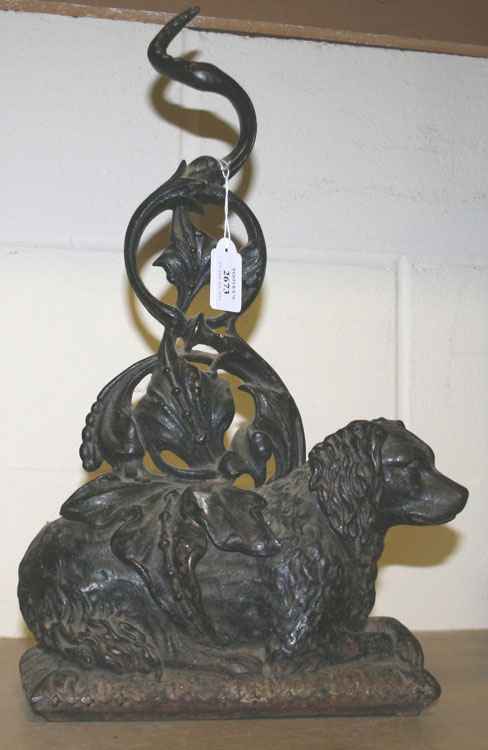 A Victorian cast iron doorstop in the form of a recumbent spaniel with a foliate scroll mount,