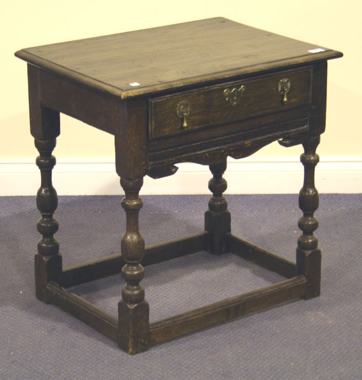 A 17th Century and later oak lowboy, the moulded top above a single drawer and shaped apron, on