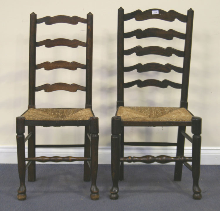 A harlequin set of eight early 20th Century ash ladder back dining chairs with rush seats, on turned