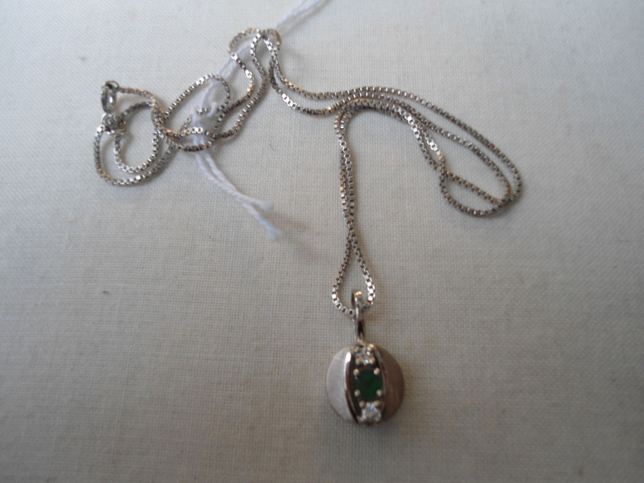 A German white gold pendant on chain set with an emerald and 2 diamonds, together with a German