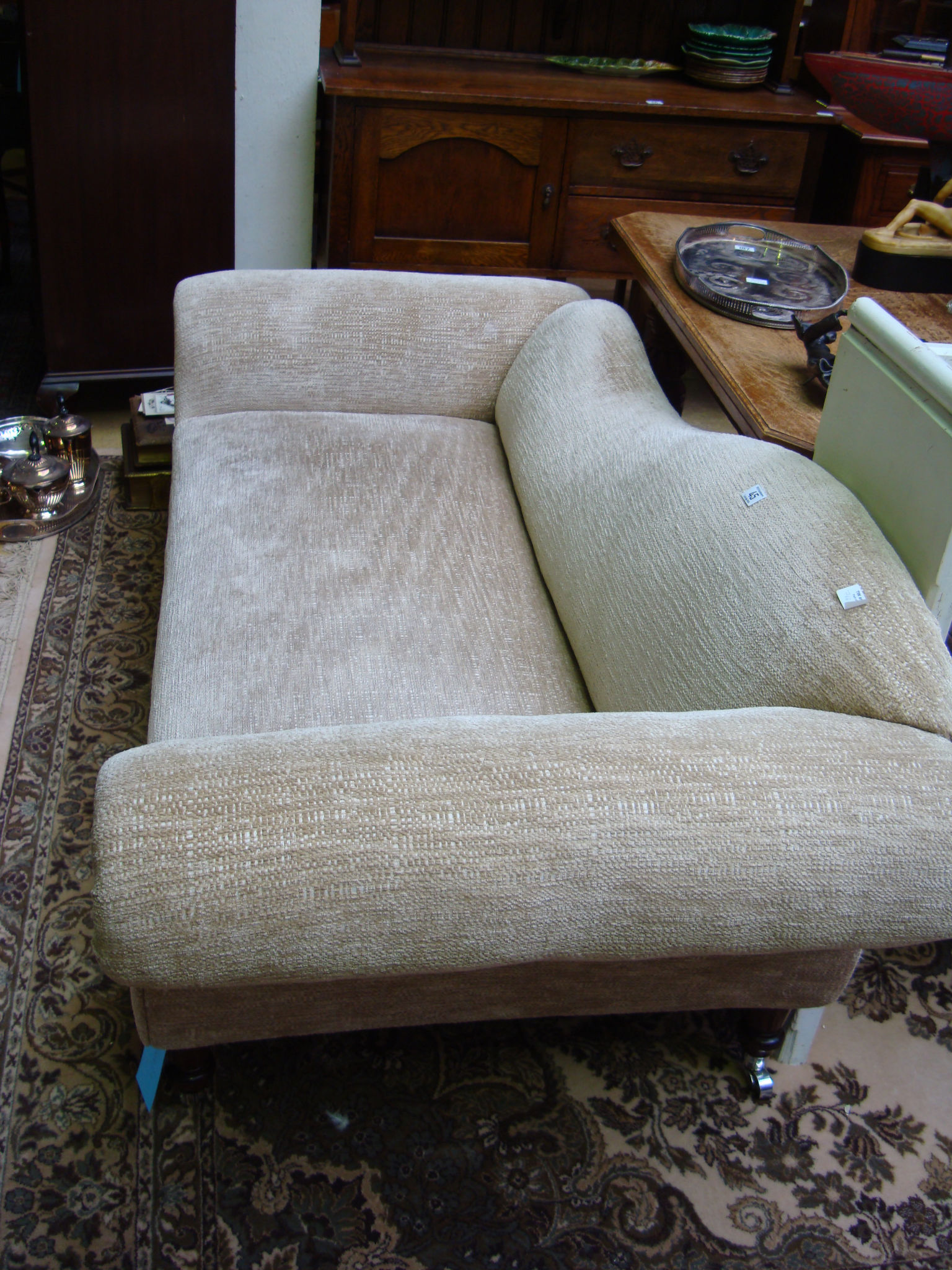 A chaise longue, upholstered in grey chenille, raised on four turned wooden legs with casters