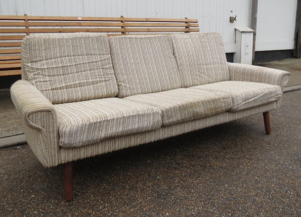 A 1960's Danish design cream wool upholstered three seater sofa raised on tapering teak legs.
