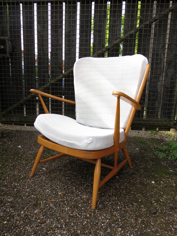 An Ercol light finish low armchair with stick back, loose cushion pads