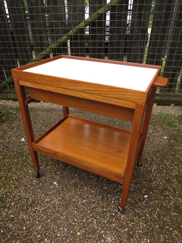 A teak trolley with removable trays and cutlery holder with dove tail construction