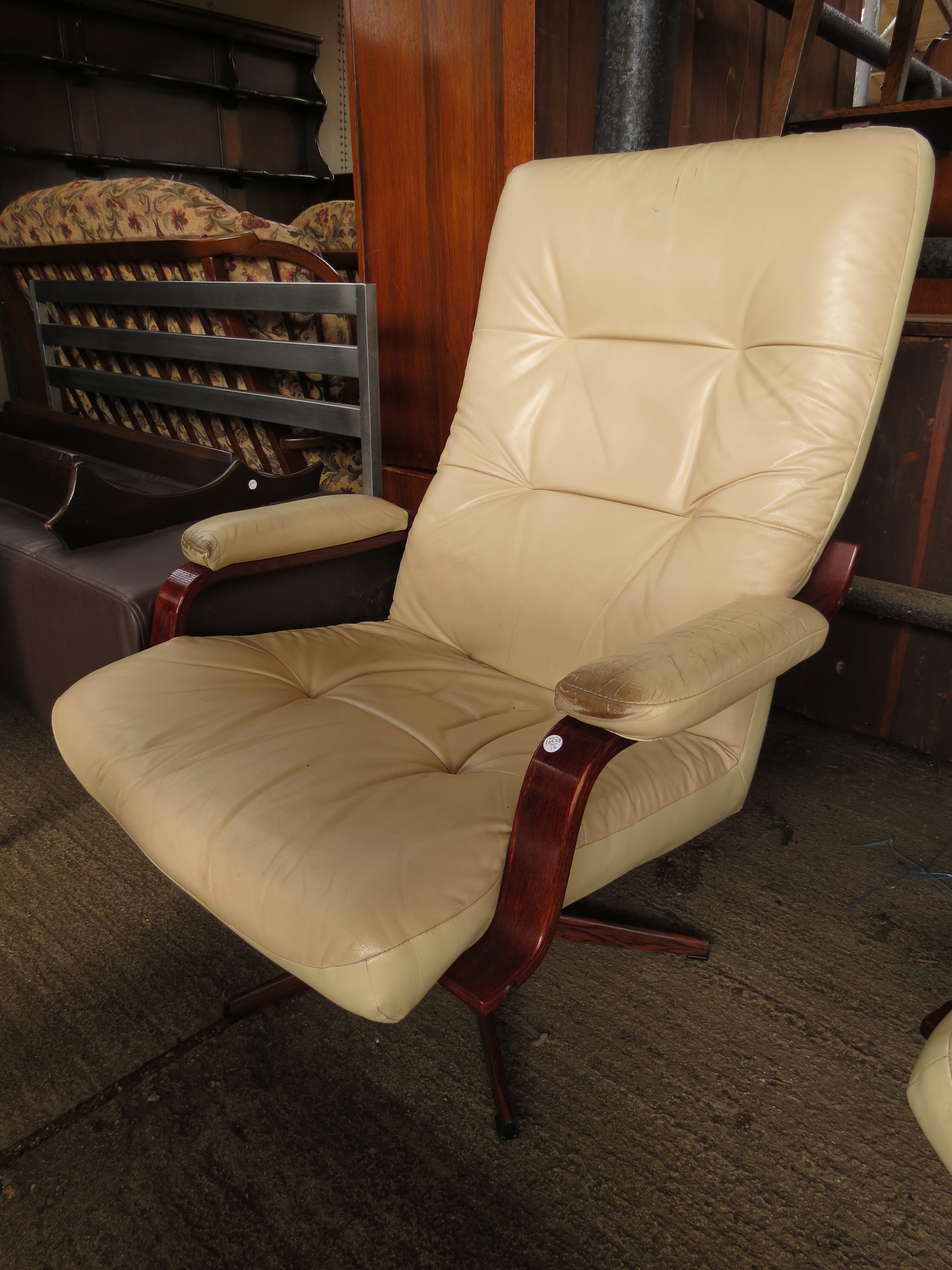 A cream upholstered swivel armchair with rosewood effect base