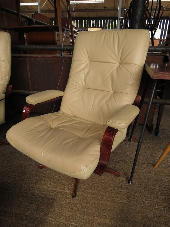 A cream upholstered swivel armchair with rosewood effect base