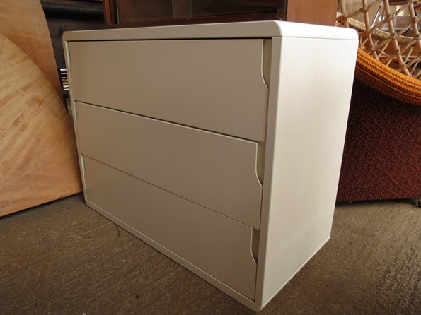 A white three drawer chest with finger grip handles