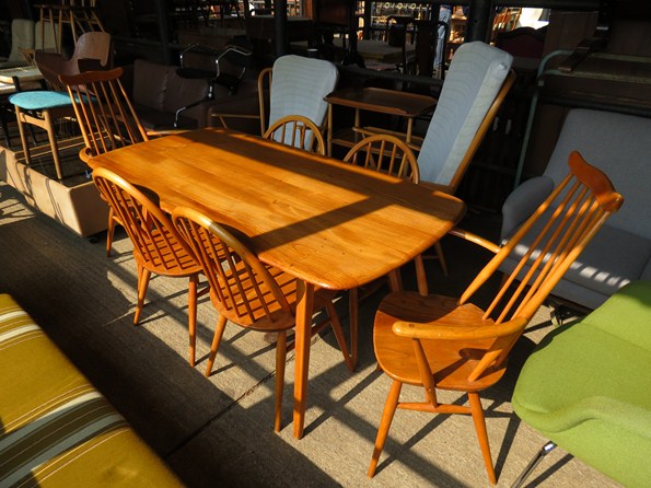 An Ercol light finish dining table with four hoop back dining chairs and two carvers with stick back