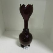 A deep red glass vase with crenellated top