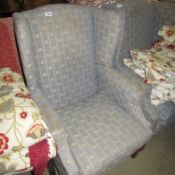 A wing armchair upholstered in fleur de lys pattern