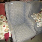 A wing armchair upholstered in fleur de lys pattern