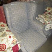 A wing armchair upholstered in fleur de lys pattern