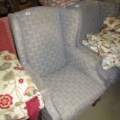 A wing armchair upholstered in fleur de lys pattern