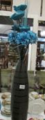 A retro style tall black glass vase with flowers