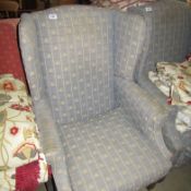 A wing armchair upholstered in fleur de lys pattern