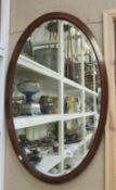 A mahogany inlaid oval bevel edged mirror