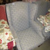 A wing armchair upholstered in fleur de lys pattern