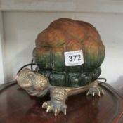 A table lamp in the shape of a tortoise with amber glass shell shade