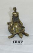 A brass pocket watch holder being man sitting on tortoise holding an Omega skeleton ball pocket