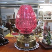 An oil lamp with cranberry glass shade