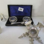 A boxed pair of silver rimmed salts, 2 plated salt spoons, and a thistle cruet (liner a/f)