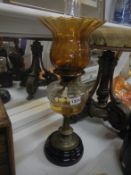 A Victorian oil lamp with glass font and amber glass shade