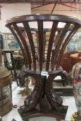 A mahogany plant stand supported by 3 dolphins