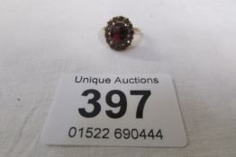 A 9ct gold ring with centre garnet surrounded by 14 smaller garnets, Size I