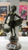 A bronze figure of a child with baskets